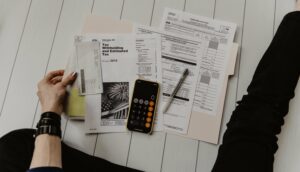 files, paper and a calculator laid out to assess a recruitment budget. 