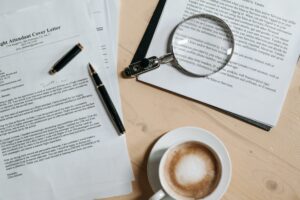 Cover letters on a desk with a magnifying glass and a cup of coffee. 