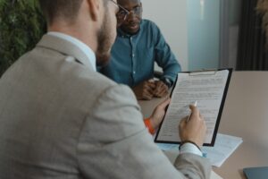 An employer looking at a candidate's recruiter resume skills on a sheet of white paper during a job interview. 